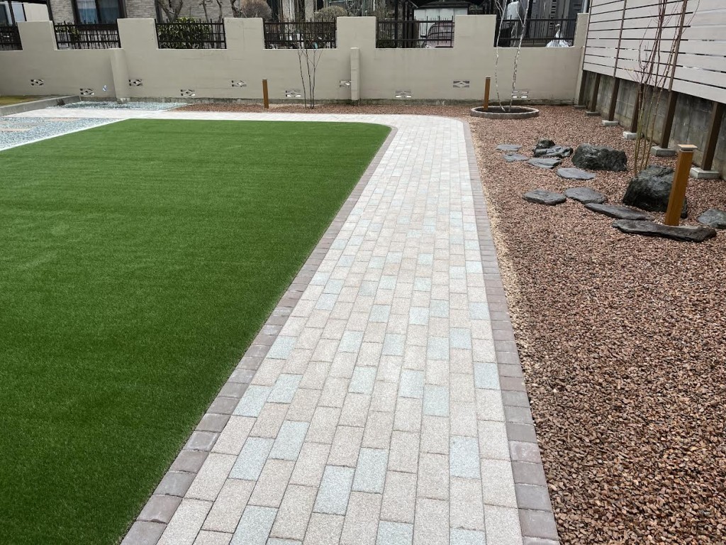 広々とした人工芝とインターロッキングのアプローチ。化粧砂利の上には景石も置かれ、素敵なお庭になりました。
